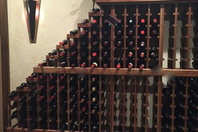 This is an example of a large country wine cellar in Denver with travertine floors and storage racks.