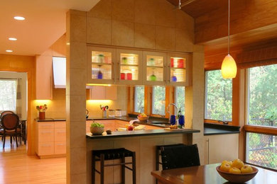 Inspiration for a mid-sized contemporary u-shaped medium tone wood floor eat-in kitchen remodel in Boston with an undermount sink, flat-panel cabinets, light wood cabinets, granite countertops, yellow backsplash, stone tile backsplash, stainless steel appliances and a peninsula