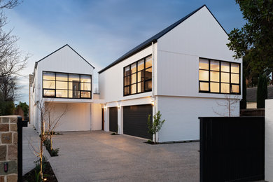 Diseño de fachada de casa blanca y negra minimalista de tamaño medio de dos plantas con revestimiento de aglomerado de cemento, tejado a dos aguas, tejado de metal y panel y listón