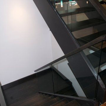 Open rise stair with glass panels and hand forged iron rails