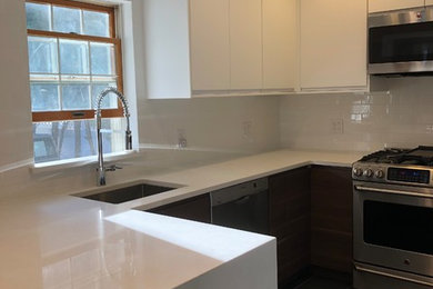 This is an example of a mid-sized contemporary u-shaped eat-in kitchen in New York with an undermount sink, flat-panel cabinets, white cabinets, quartz benchtops, white splashback, subway tile splashback, stainless steel appliances, porcelain floors, a peninsula, grey floor and white benchtop.