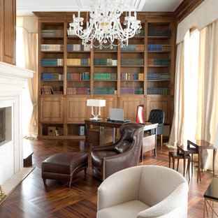Inspiration for a mid-sized eclectic home office in Vancouver with a library, brown walls, medium hardwood floors, a two-sided fireplace, a stone fireplace surround, a freestanding desk and brown floor.