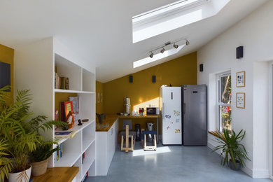 Inspiration for a medium sized modern grey and yellow open plan living room in London with a home bar, yellow walls, laminate floors, no fireplace, no tv, grey floors, brick walls and feature lighting.