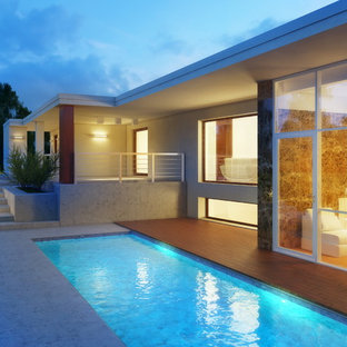 Foto på en mellanstor funkis ovanmarkspool framför huset, med poolhus