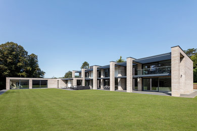 This is an example of a large and gey modern two floor brick and rear detached house in Oxfordshire with a flat roof, a mixed material roof and a grey roof.