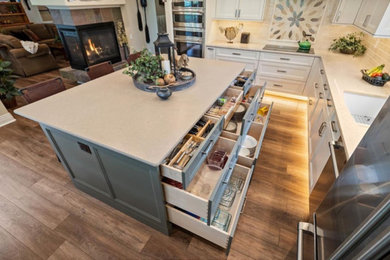 Open concept kitchen - mid-sized cottage l-shaped medium tone wood floor and brown floor open concept kitchen idea in Denver with an undermount sink, recessed-panel cabinets, green cabinets, beige backsplash, subway tile backsplash, stainless steel appliances, an island and beige countertops