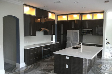 Example of a trendy l-shaped multicolored floor open concept kitchen design in Miami with an undermount sink, flat-panel cabinets, dark wood cabinets, beige backsplash, stainless steel appliances and an island