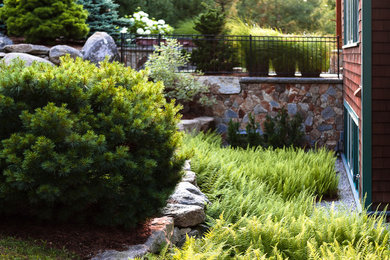 Design ideas for a large traditional backyard partial sun garden for summer in Portland Maine with a retaining wall and gravel.