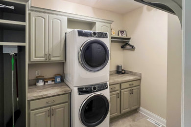 Inspiration for a small transitional galley dedicated laundry room remodel in Cleveland with raised-panel cabinets, green cabinets, laminate countertops, a stacked washer/dryer and beige countertops