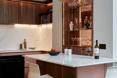Inspiration for a small contemporary l-shaped home bar in London with an integrated sink, louvered cabinets, red cabinets, quartz worktops, beige splashback, engineered quartz splashback, ceramic flooring, brown floors and beige worktops.