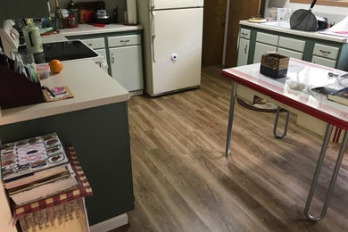 Inspiration for a mid-sized rustic l-shaped medium tone wood floor and brown floor enclosed kitchen remodel in Other with a double-bowl sink, flat-panel cabinets, green cabinets, white appliances and an island