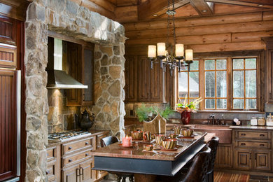 Example of a mountain style kitchen design in Other with a farmhouse sink, raised-panel cabinets, paneled appliances, an island and slate backsplash