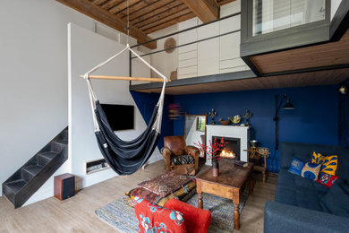 Cette photo montre un grand salon ouvert avec un mur bleu, un téléviseur fixé au mur, poutres apparentes et un escalier.