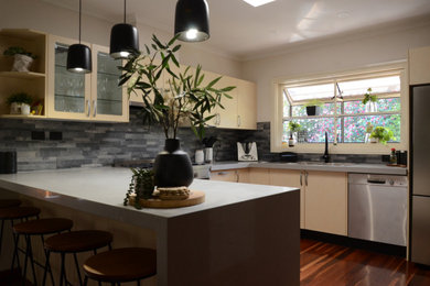 Design ideas for a mid-sized contemporary u-shaped eat-in kitchen in Melbourne with a double-bowl sink, yellow cabinets, quartz benchtops, grey splashback, slate splashback, stainless steel appliances, with island and grey benchtop.