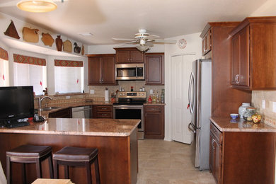 Inspiration for a mid-sized timeless u-shaped ceramic tile eat-in kitchen remodel in Phoenix with a drop-in sink, dark wood cabinets, granite countertops, beige backsplash, ceramic backsplash, stainless steel appliances, no island and recessed-panel cabinets