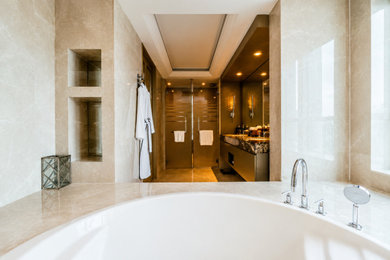 Inspiration for a huge contemporary master beige tile and marble tile marble floor, beige floor, double-sink and tray ceiling bathroom remodel in Edmonton with flat-panel cabinets, brown cabinets, a wall-mount toilet, beige walls, an undermount sink, marble countertops, a hinged shower door, beige countertops, a niche and a built-in vanity