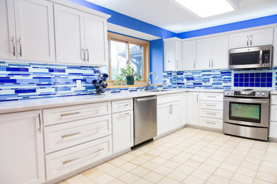 This is an example of a mid-sized contemporary l-shaped eat-in kitchen in Other with an undermount sink, white cabinets, laminate benchtops, blue splashback, stainless steel appliances, flat-panel cabinets, glass tile splashback, ceramic floors, no island, beige floor and white benchtop.