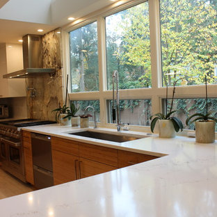 Idées déco pour une grande arrière-cuisine moderne en U avec un évier encastré, un placard à porte plane, des portes de placard oranges, un plan de travail en granite, une crédence blanche, un électroménager en acier inoxydable, un sol en carrelage de porcelaine, un îlot central, un sol blanc et un plan de travail beige.