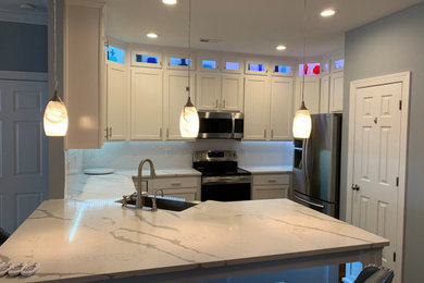 Mid-sized minimalist u-shaped eat-in kitchen photo in Charlotte with shaker cabinets, white cabinets, quartz countertops and subway tile backsplash