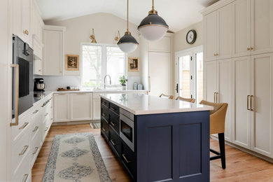 Eat-in kitchen - mid-sized transitional u-shaped light wood floor, brown floor and vaulted ceiling eat-in kitchen idea in Toronto with an undermount sink, shaker cabinets, white cabinets, quartz countertops, white backsplash, quartz backsplash, paneled appliances, an island and white countertops