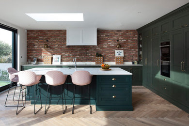 Diseño de cocina contemporánea grande con armarios estilo shaker, puertas de armario verdes, encimera de cuarzo compacto, una isla y suelo marrón