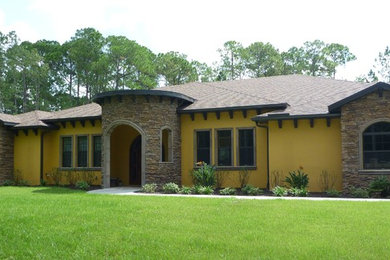 Inspiration for a large mediterranean one-storey yellow house exterior in Tampa with stone veneer, a hip roof and a shingle roof.