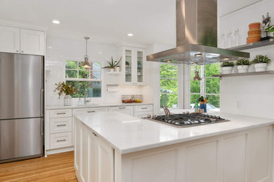 Eat-in kitchen - mid-sized cottage single-wall medium tone wood floor and brown floor eat-in kitchen idea in Portland with an undermount sink, recessed-panel cabinets, white cabinets, quartzite countertops, white backsplash, ceramic backsplash, paneled appliances, an island and white countertops