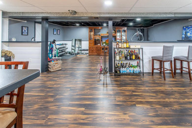 Example of a vinyl floor and shiplap wall basement design in New York with a bar