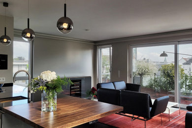 Zweizeilige, Mittelgroße Moderne Wohnküche mit Unterbauwaschbecken, flächenbündigen Schrankfronten, grauen Schränken, Küchenrückwand in Weiß, Küchengeräten aus Edelstahl, braunem Holzboden, Kücheninsel, braunem Boden, schwarzer Arbeitsplatte und Arbeitsplatte aus Holz in Hannover