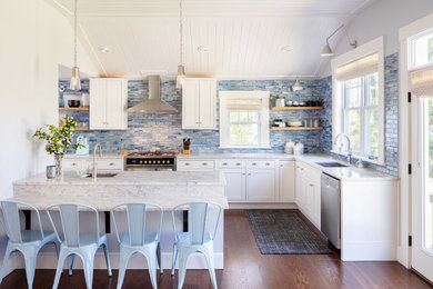 Design ideas for a beach style l-shaped kitchen in Providence with an undermount sink, shaker cabinets, white cabinets, blue splashback, stainless steel appliances, medium hardwood floors, a peninsula and white benchtop.