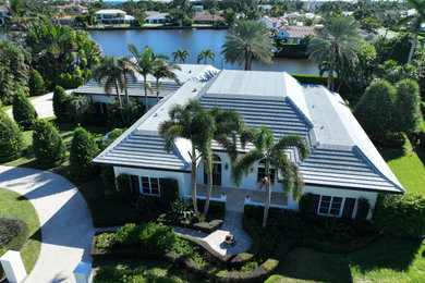 Example of a large french country white one-story exterior home design in Other with a tile roof and a gray roof