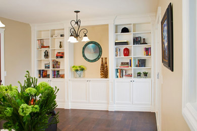 Example of a mid-sized trendy dark wood floor and brown floor living room library design in Calgary with beige walls, no fireplace and no tv