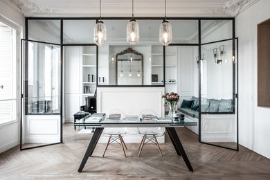 This is an example of an expansive contemporary home office in Paris with white walls, light hardwood floors, a freestanding desk and brown floor.