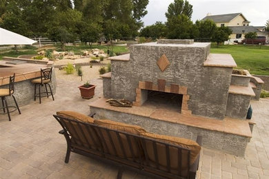 Example of a large classic backyard brick patio design in Phoenix with a fire pit and no cover