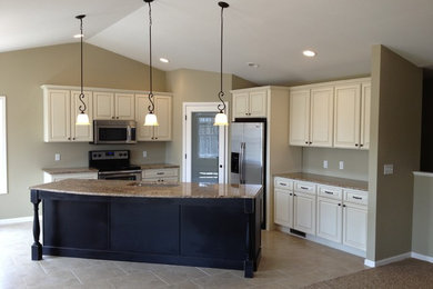 Inspiration for a transitional porcelain tile kitchen remodel in Other with an undermount sink, raised-panel cabinets, black cabinets, granite countertops, beige backsplash and stainless steel appliances