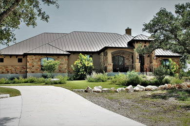 Large elegant beige one-story stone house exterior photo in Other with a hip roof and a metal roof