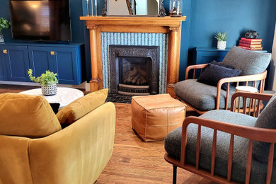 Example of a mid-sized eclectic medium tone wood floor family room design in Denver with blue walls, a standard fireplace and a tile fireplace