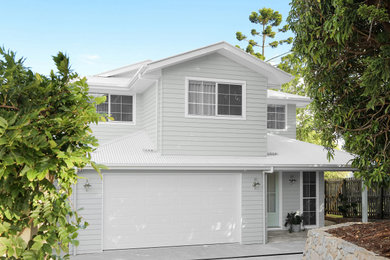 Imagen de fachada de casa blanca costera de tamaño medio de dos plantas con revestimiento de aglomerado de cemento, tejado a cuatro aguas, tejado de metal y panel y listón