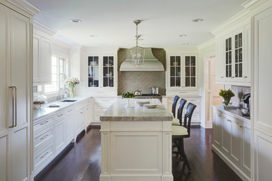 Example of a classic dark wood floor kitchen design in Chicago with an undermount sink, glass-front cabinets, white cabinets, gray backsplash and an island