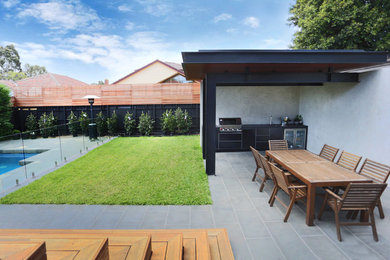 Imagen de patio minimalista grande en patio trasero con cocina exterior, adoquines de piedra natural y pérgola