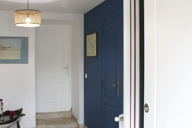 Cette image montre une entrée rustique avec un mur bleu, un sol en travertin et un sol beige.