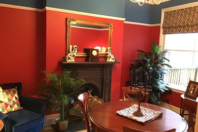 This is an example of a medium sized victorian dining room in Cheshire with red walls, light hardwood flooring, a standard fireplace, a metal fireplace surround and brown floors.