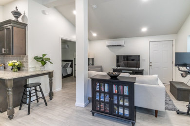 Small transitional open concept laminate floor, beige floor and vaulted ceiling living room photo in Cleveland with white walls, no fireplace and a tv stand