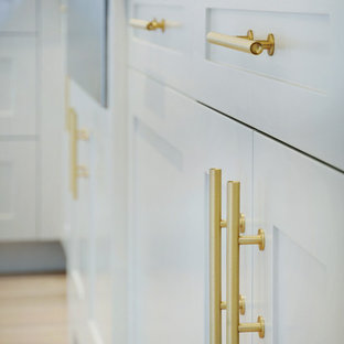 Diseño de cocina en L, minimalista, con fregadero bajoencimera, armarios estilo shaker, puertas de armario blancas, encimera de cuarzo compacto, salpicadero blanco, electrodomésticos de acero inoxidable y una isla