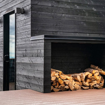 Beautiful outdoor wood burning sauna on a deck with a covered area and built-ins