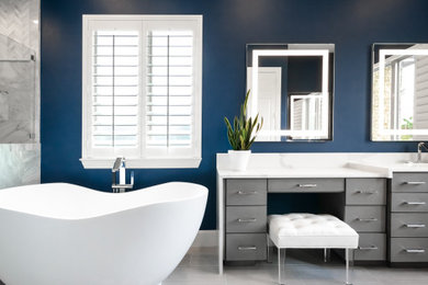Inspiration for a large modern master bathroom in Portland with flat-panel cabinets, grey cabinets, a freestanding tub, a curbless shower, a bidet, white tile, marble, blue walls, porcelain floors, an undermount sink, quartzite benchtops, grey floor, a hinged shower door, white benchtops, an enclosed toilet, a double vanity and a built-in vanity.