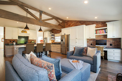 Inspiration for a mid-sized transitional galley medium tone wood floor open concept kitchen remodel in Orange County with a single-bowl sink, recessed-panel cabinets, beige cabinets, solid surface countertops, stainless steel appliances, an island, brown backsplash and brick backsplash