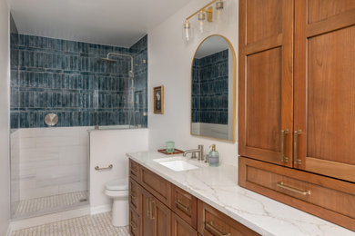 Inspiration for a mid-sized transitional master blue tile and ceramic tile mosaic tile floor, beige floor and single-sink bathroom remodel in Baltimore with shaker cabinets, brown cabinets, a two-piece toilet, beige walls, an undermount sink, quartz countertops, beige countertops, a niche and a built-in vanity