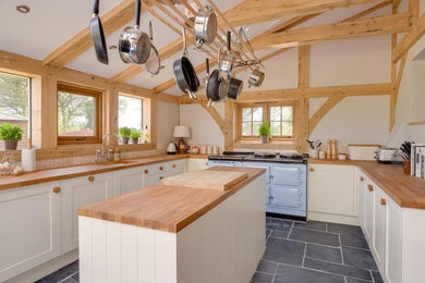 Photo of a country u-shaped kitchen in Sussex with a single-bowl sink, shaker cabinets, white cabinets, wood benchtops, beige splashback, coloured appliances and with island.