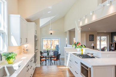 Eat-in kitchen - huge transitional medium tone wood floor and brown floor eat-in kitchen idea in Denver with an undermount sink, shaker cabinets, white cabinets, quartz countertops and white countertops